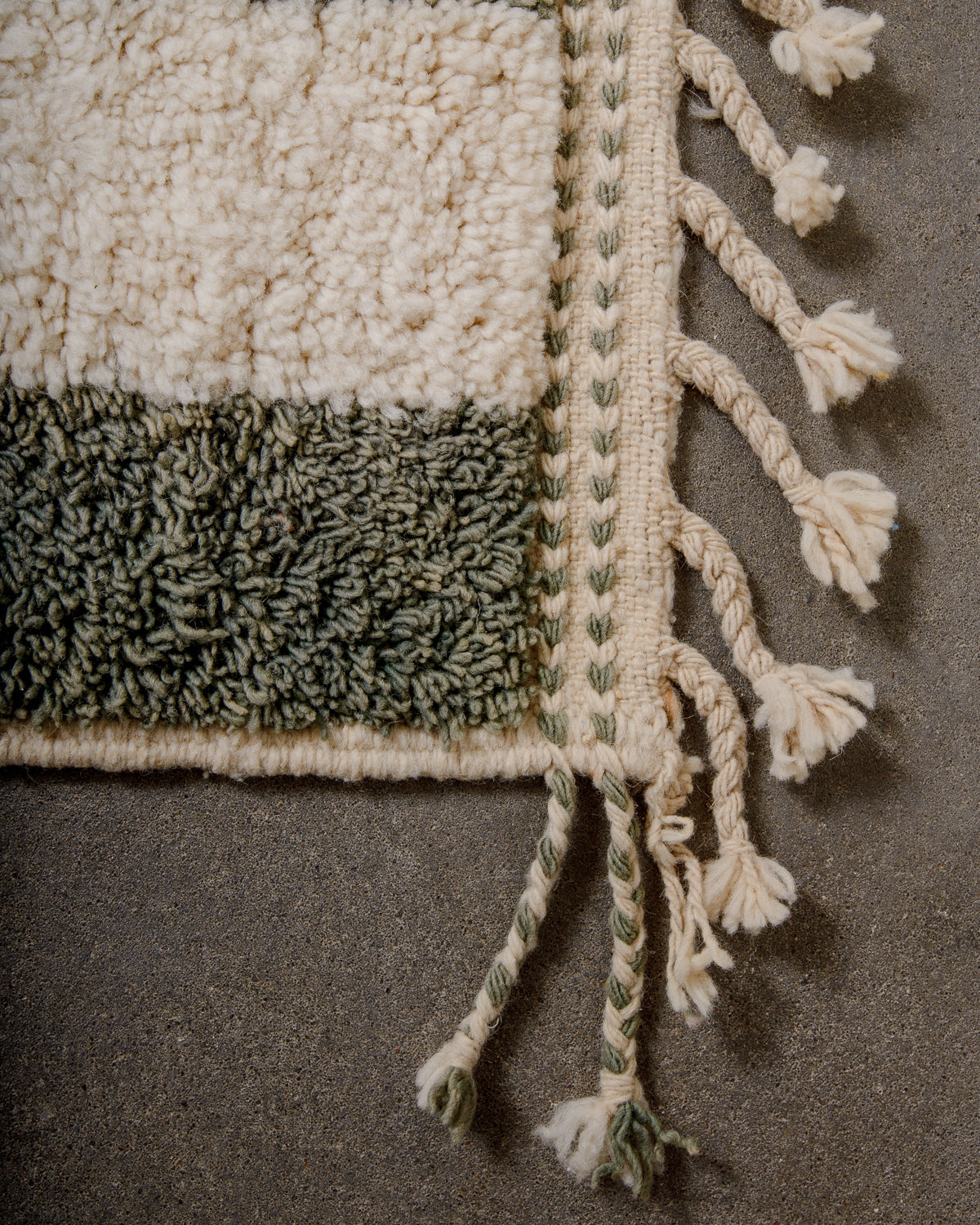 Corner of Berber runner rug with a woven edge and natural wool tassels.